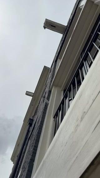 A low-angle shot of a white apartment building with black windows and balcony on a cloudy day